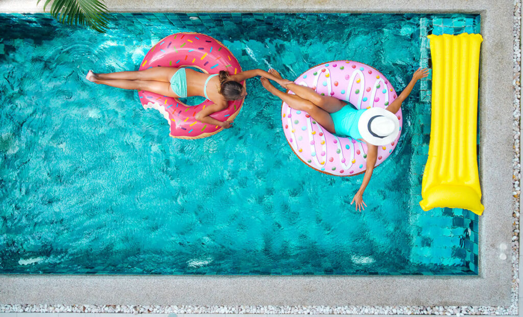 People relaxing on inflatable ring in pool