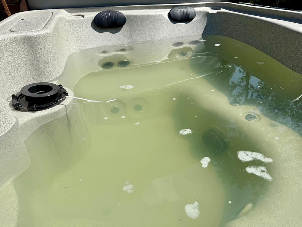 Neglected outdoor jacuzzi filled with murky green water