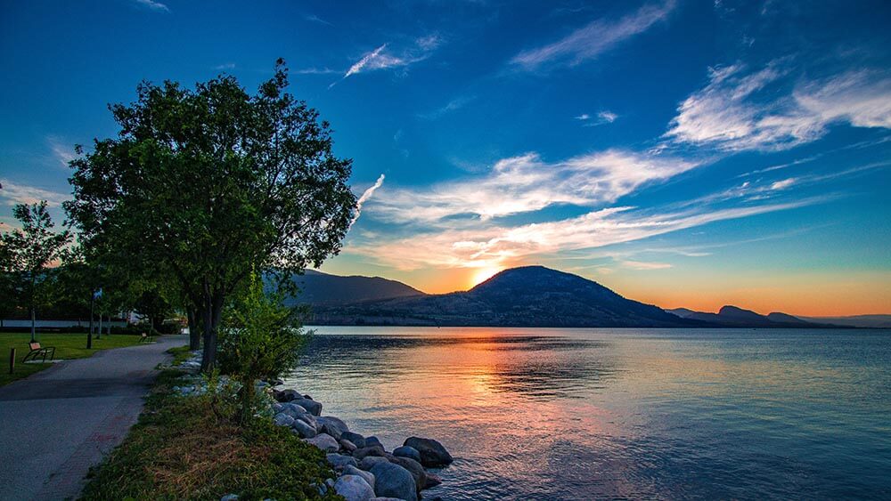 Penticton park as the sun sets behind a mountain onto okanagan lake